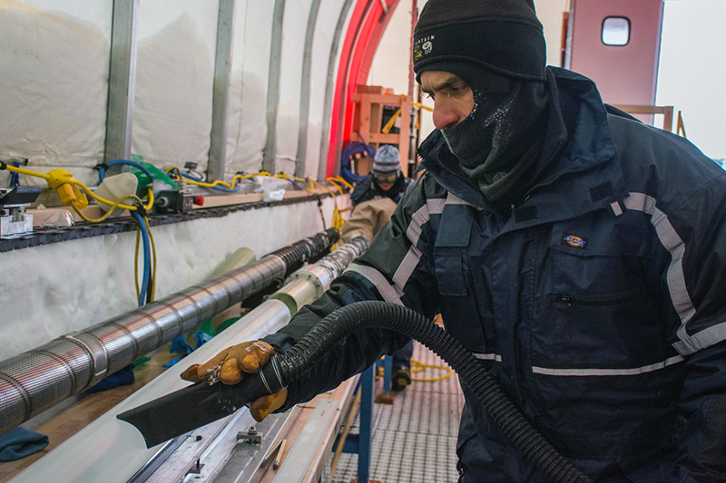 Murat Aydin cleans cutting fluid off of a recent ice core as he prepares it for storage