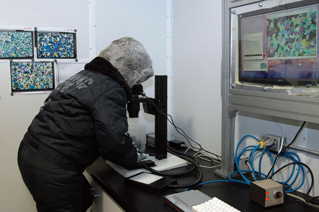 USGS scientist Joan Fitzpatrick looks at a thin section of ice core, analyzing the pattern of individual ice crystals