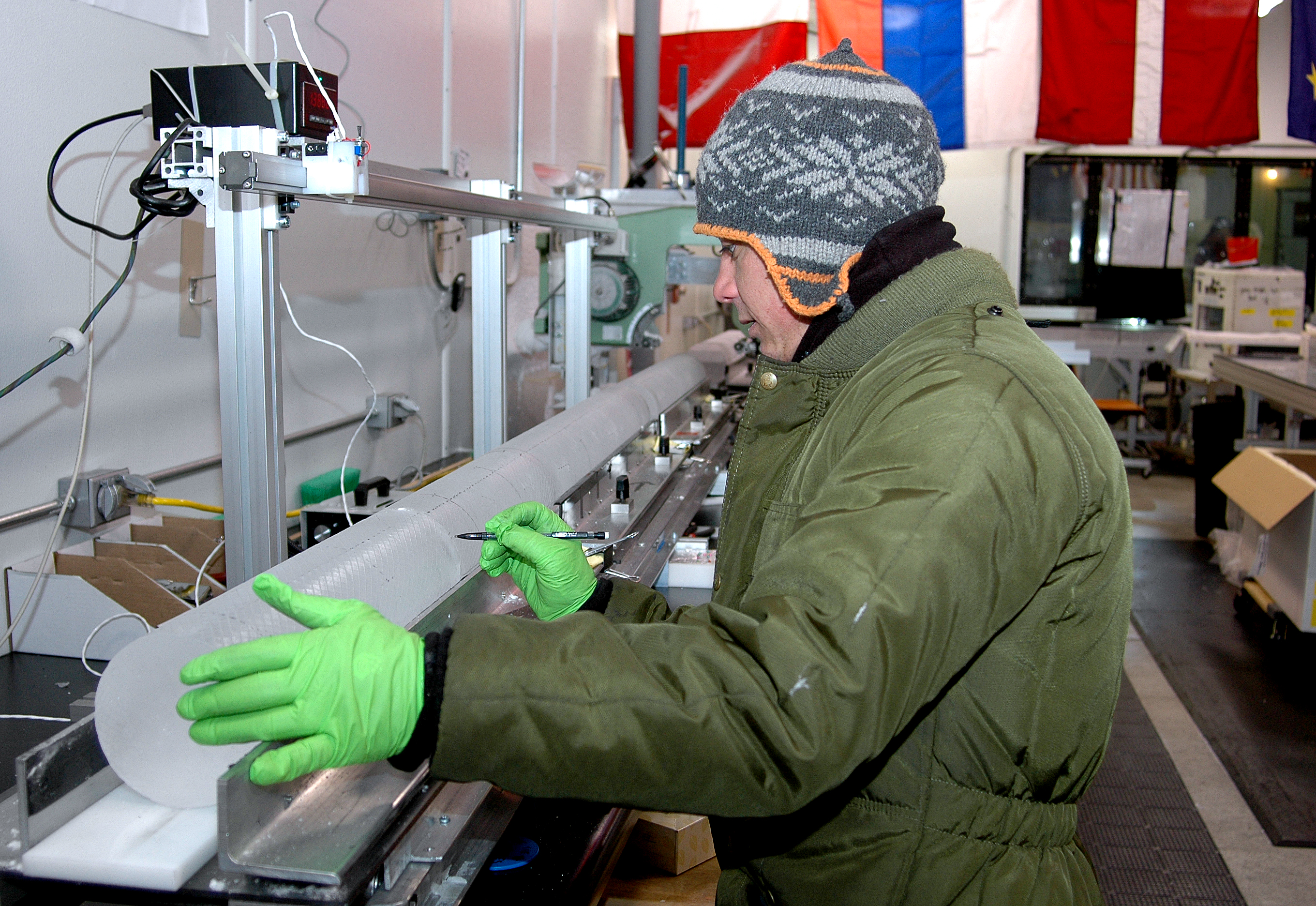 Science technician Tommy Cox measures a section of the WAIS Divide ice core as it begins its journey down the core processing line at the National Ice Core Laboratory near Denver